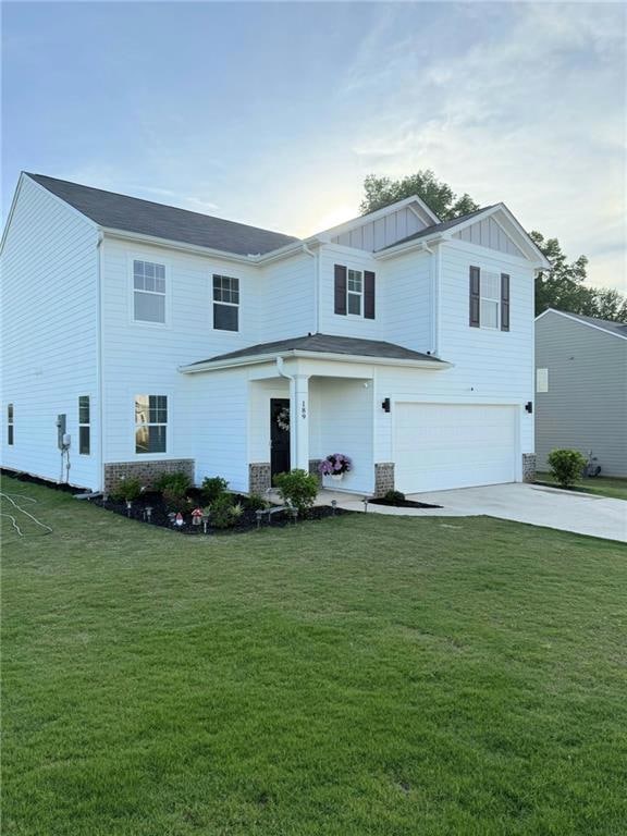 View of front facade with a garage, board and batten siding, driveway, and a front yard