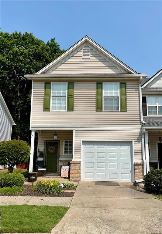 View of front of house with covered porch, an attached garage, driveway, and brick siding