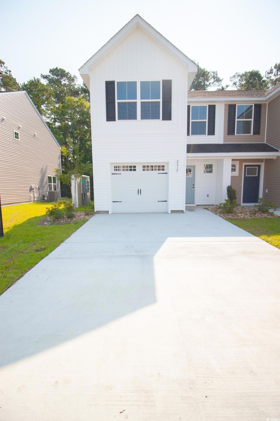 View of front of property with a garage, board and batten siding, a front lawn, and driveway