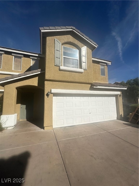 View of front of house with stucco siding, a garage, and concrete driveway