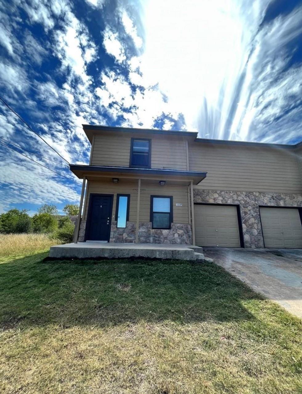 View of front facade with a front yard, stone sid