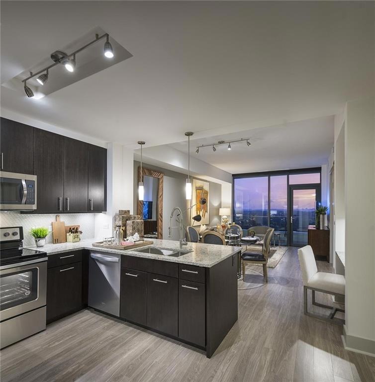Kitchen with kitchen peninsula, backsplash, track lighting, sink, and appliances with stainless steel finishes