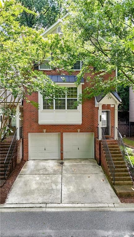 View of front of property featuring a garage, concrete driveway, and brick siding