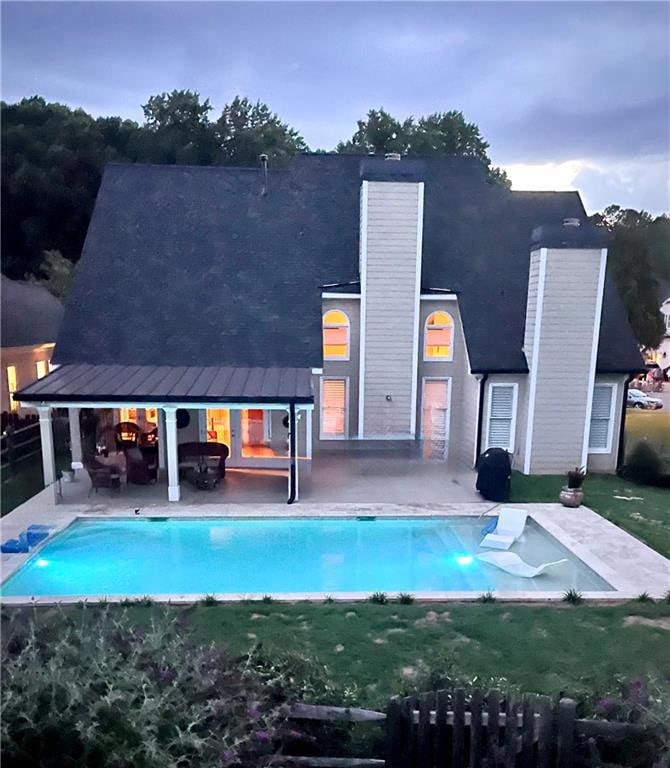 Twilight view of salt water, gunite pool and covered patio