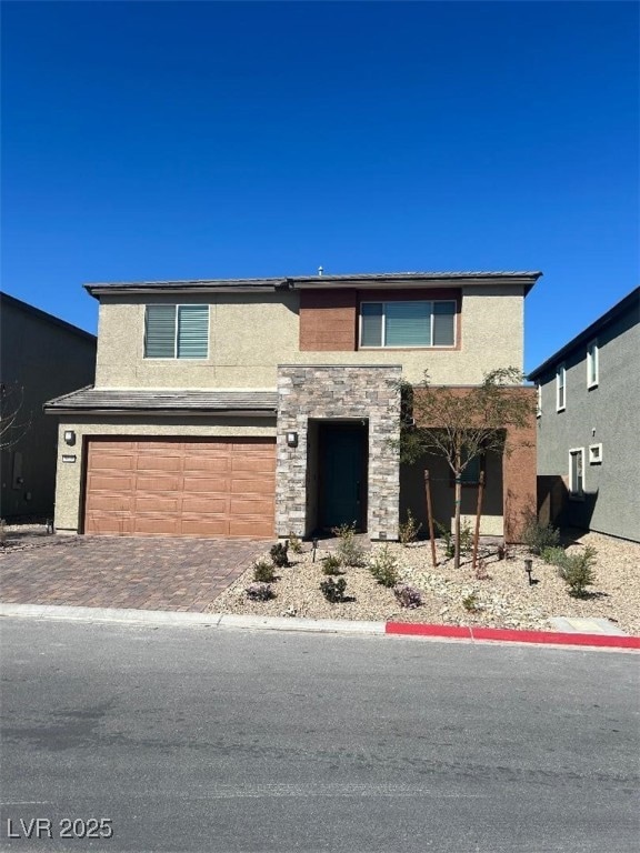 View of front of home featuring a garage, stone si