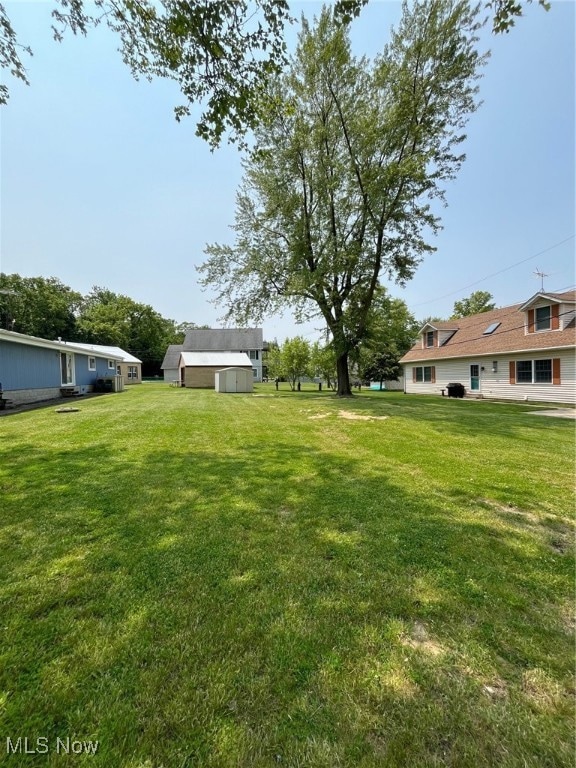 View of grassy yard featuring a storage shed