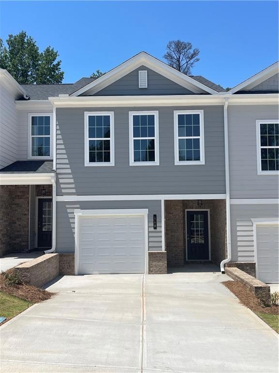 View of front facade with driveway, an attached garage, and brick siding