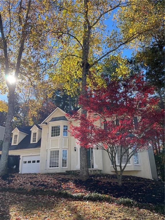 View of front facade with a garage and stucco siding
