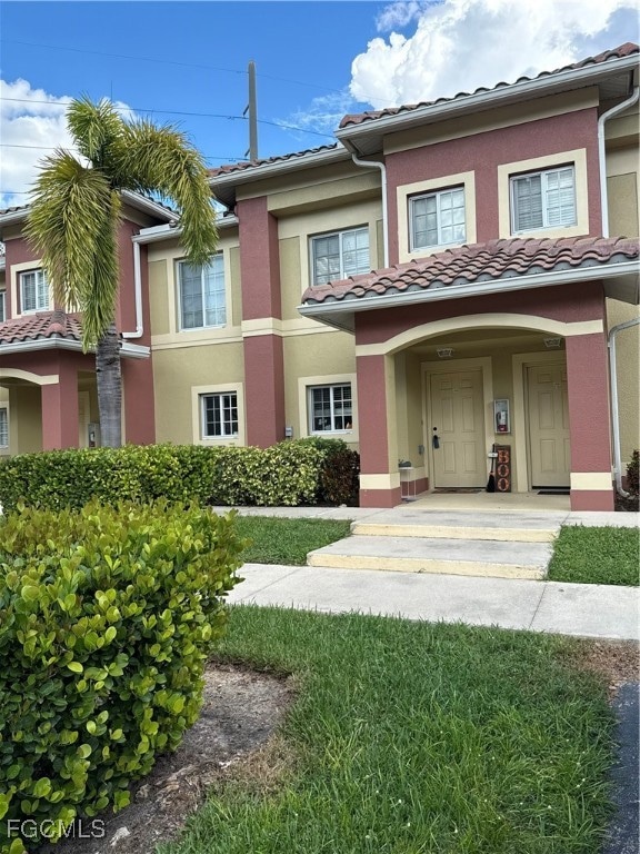Mediterranean / Spanish townhome featuring covered porch, stucco siding, and a tiled roof.