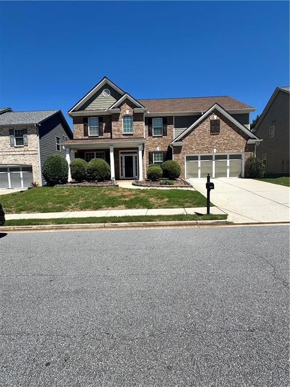 Traditional home featuring driveway, a garage, brick siding, and a front yard