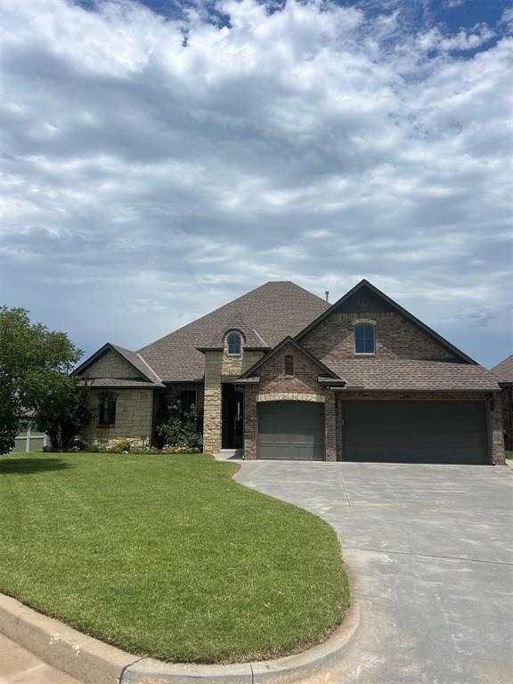 View of front of property with driveway, a front lawn, an attached garage, roof with shingles, and stone siding
