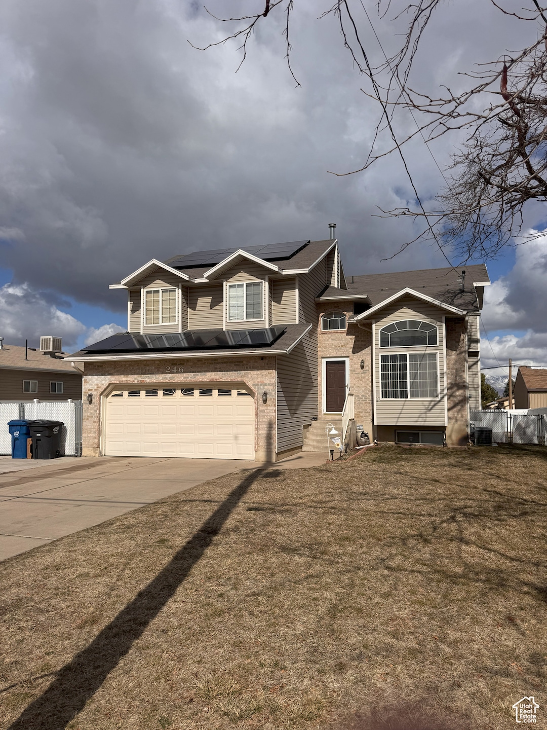 View of front facade featuring fence, an attached garage, entry steps, concrete driveway, and brick siding