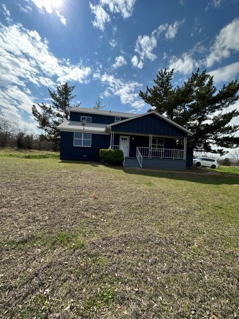 View of front of property featuring covered porch, a front yard, and board and batten siding