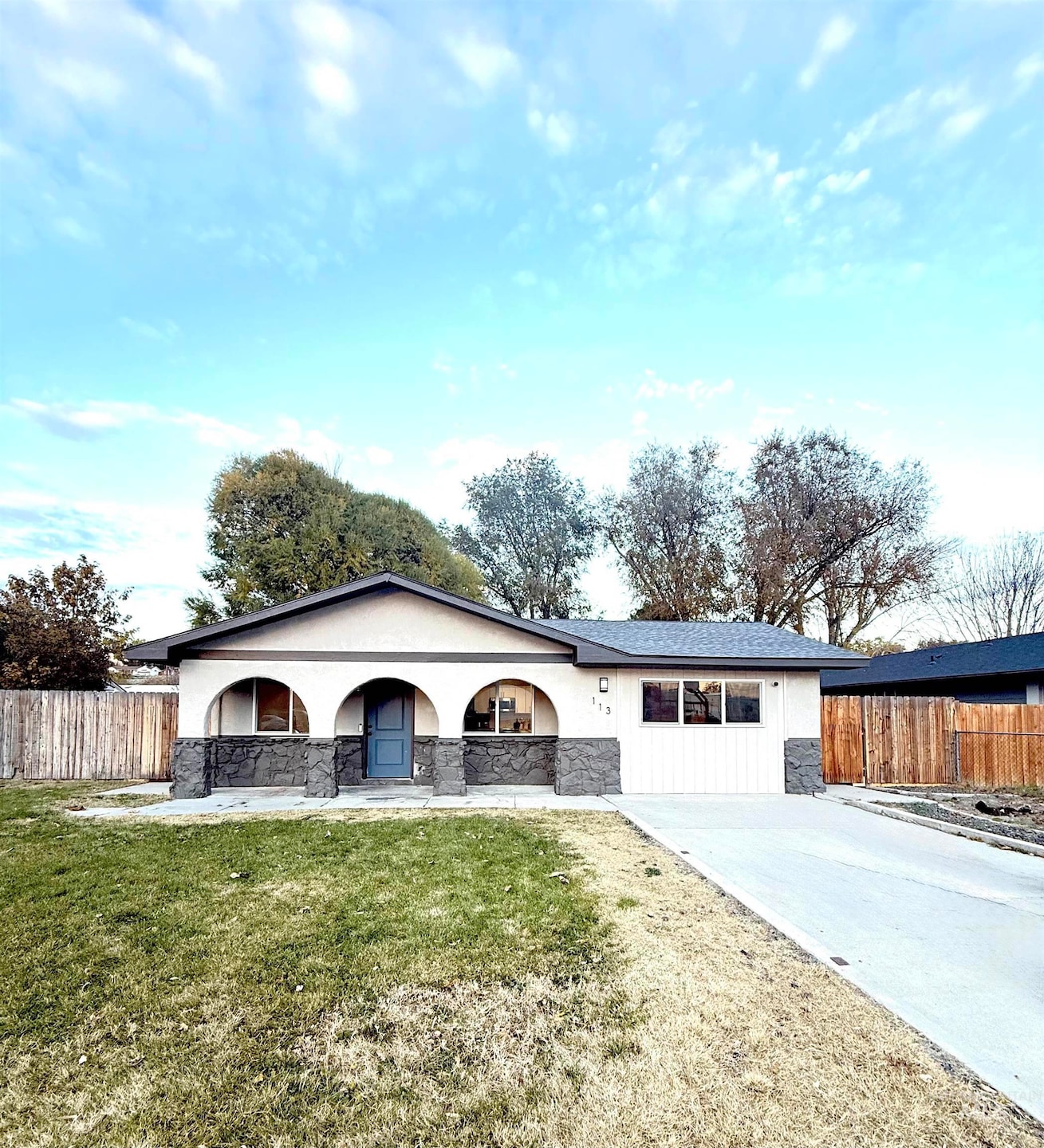 Single story home featuring a porch, stone siding, stucco siding, and concrete driveway