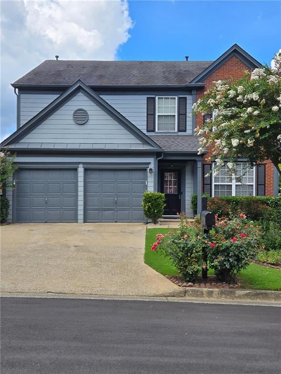 Traditional-style house with concrete driveway, roof with shingles, and an attached garage