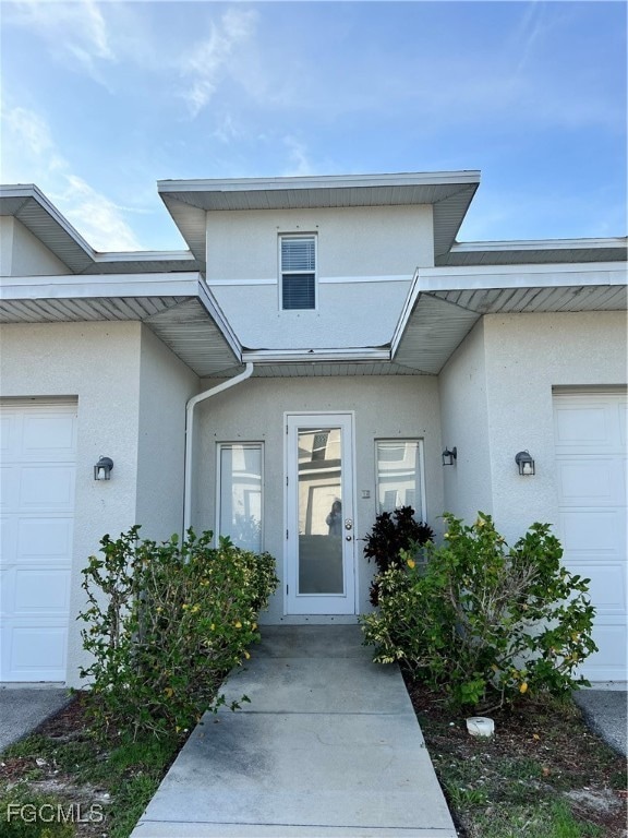 Property entrance with stucco siding and a garage