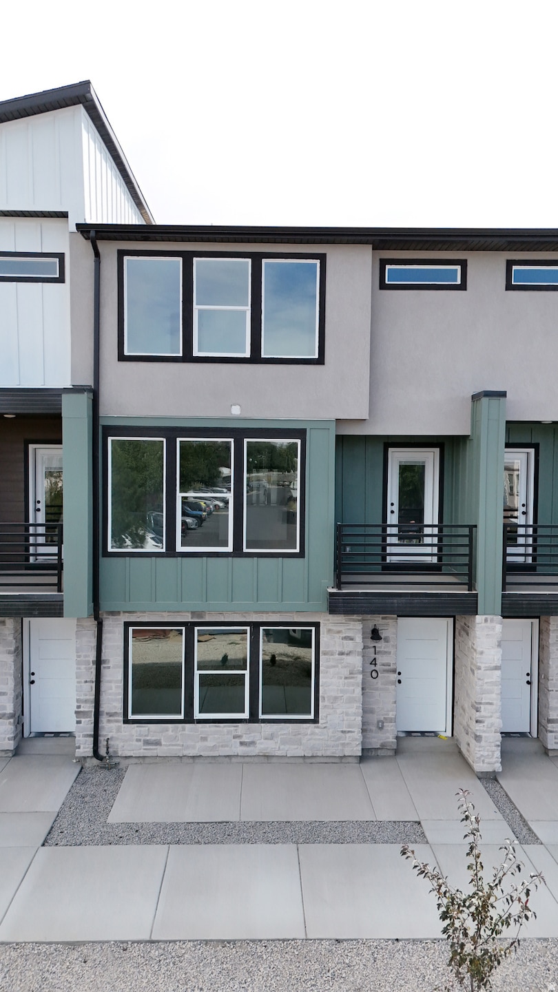 Contemporary home with a balcony, board and batten siding, stucco siding, and stone siding