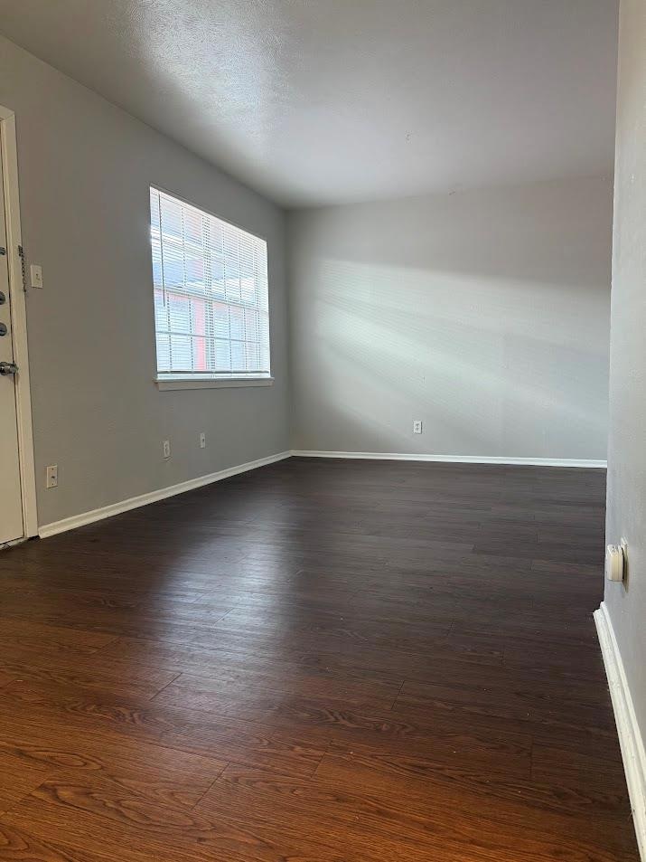 Empty room featuring baseboards and dark wood fin