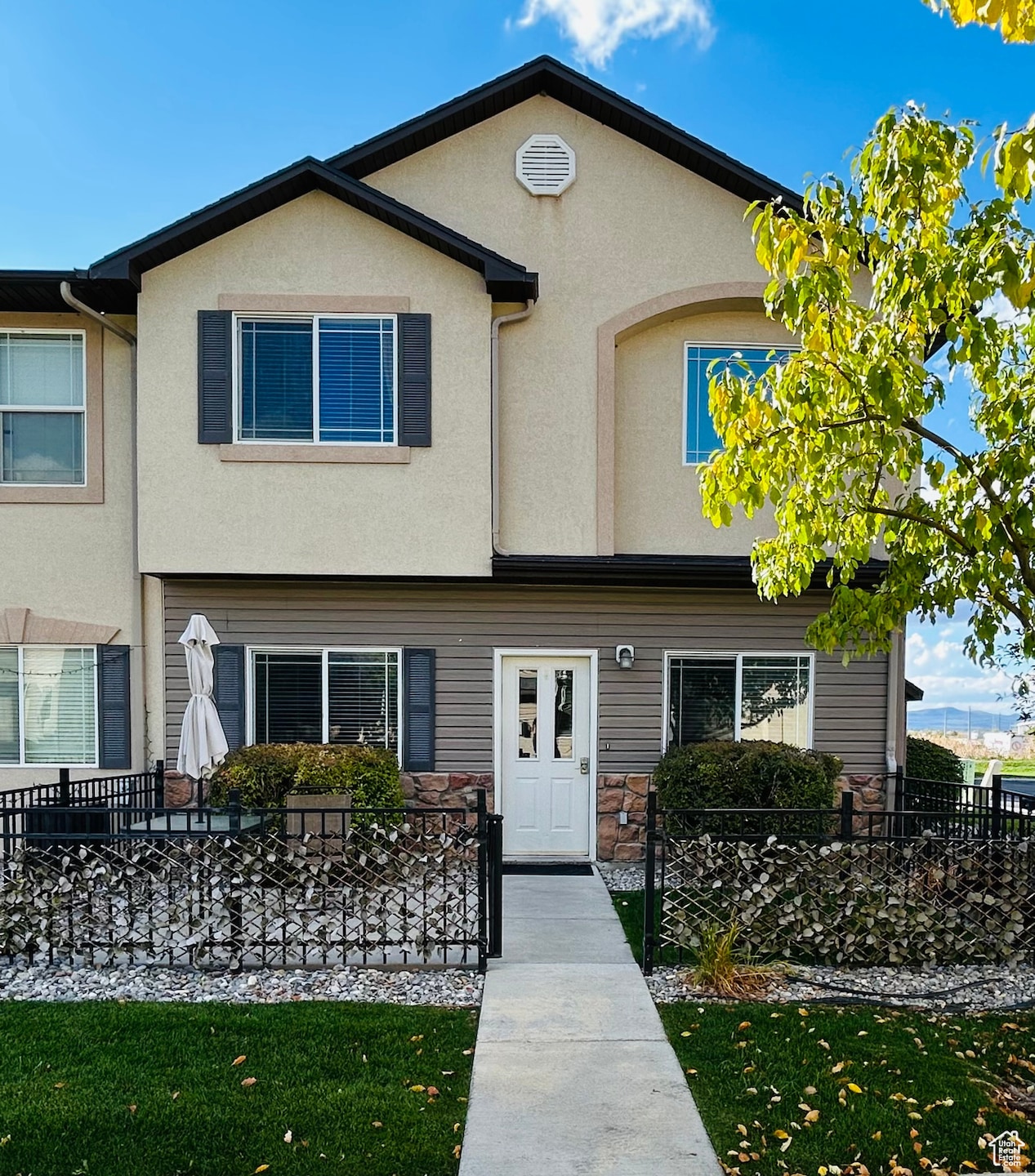 View of front of property with stucco siding, a fenced front yard, and stone siding
