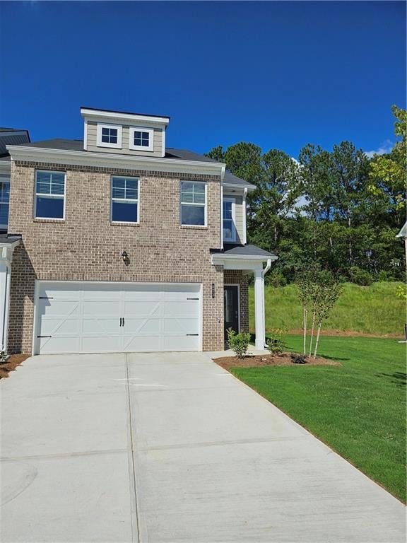 View of front facade with brick siding, driveway, a garage, and a front yard