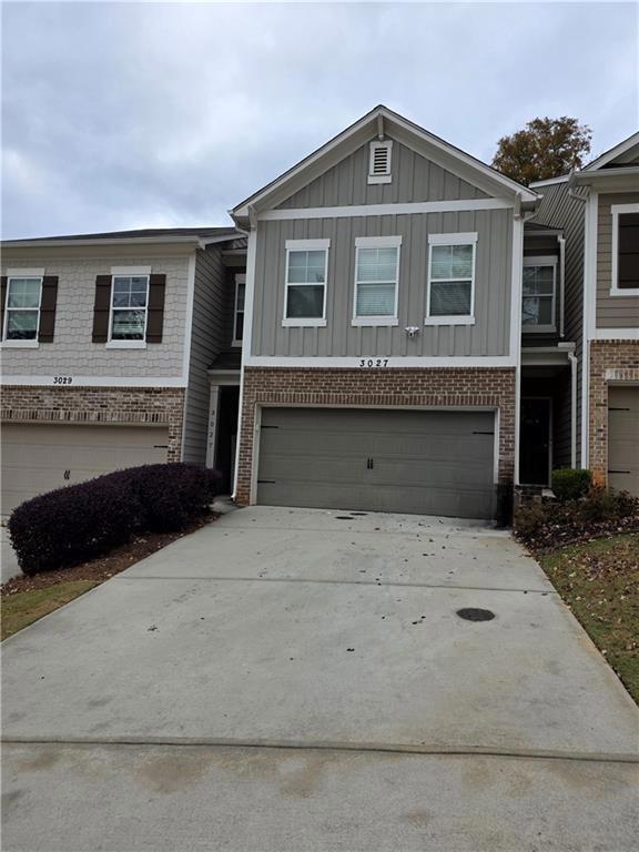 Craftsman inspired home featuring concrete driveway, brick siding, board and batten siding, and an attached garage