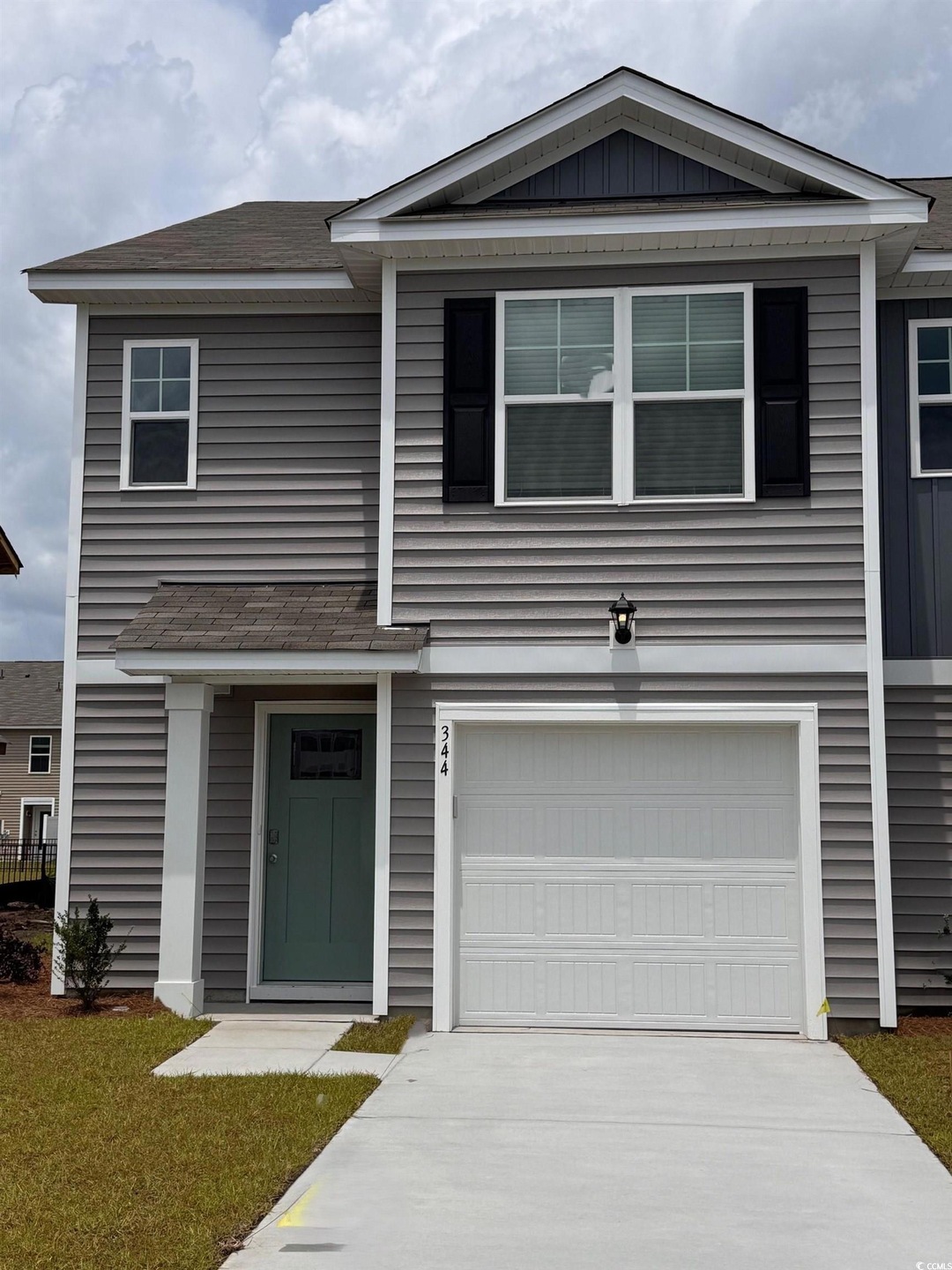 View of front facade featuring an attached garage, concrete driveway, and a shingled roof