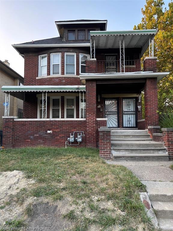 View of front facade featuring brick siding, a balcony, and a front lawn