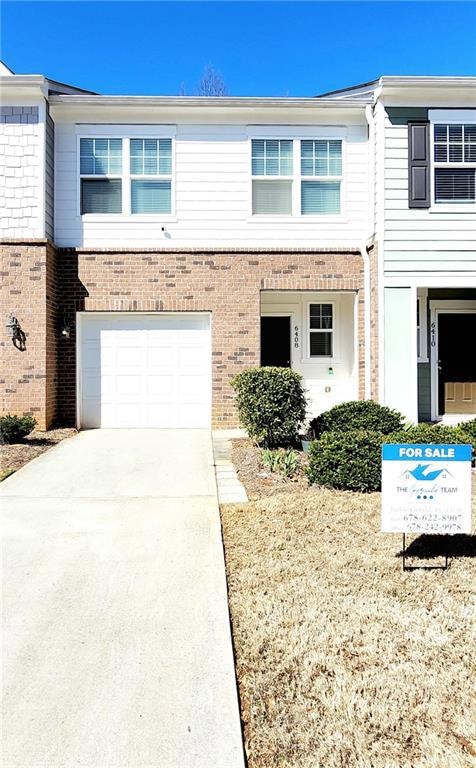 View of property with concrete driveway, brick sid
