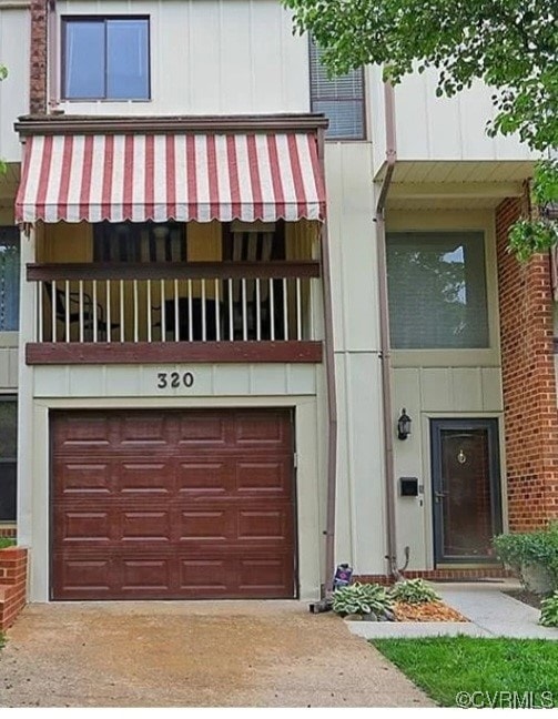 View of front of property featuring a balcony and a garage