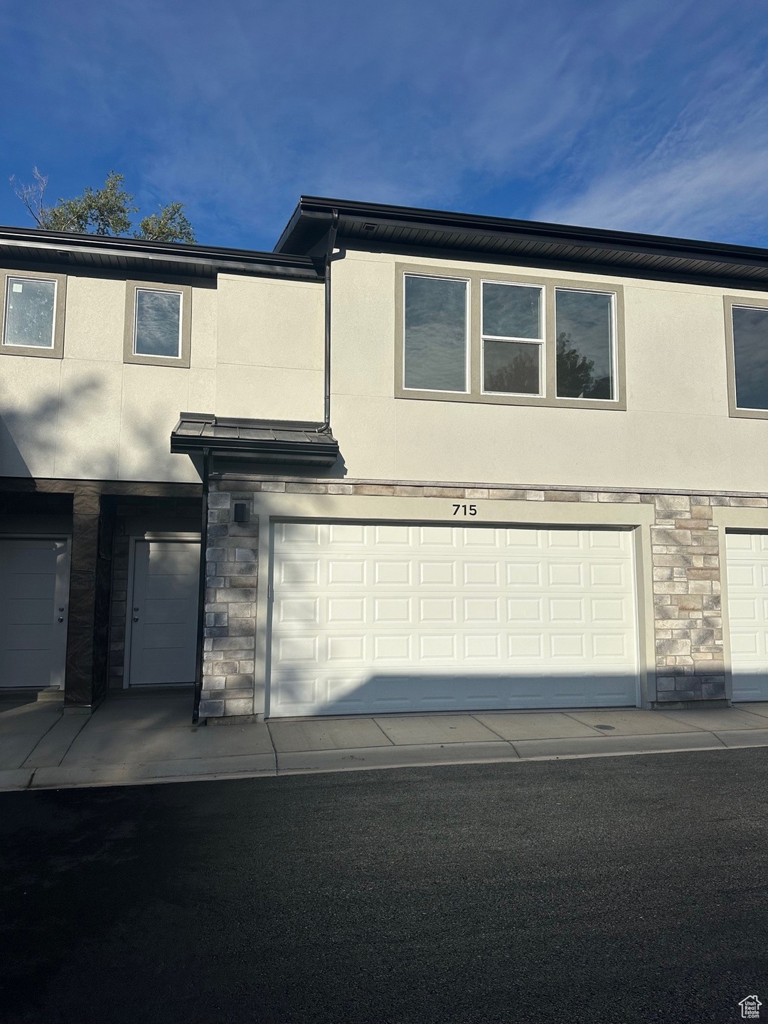 View of side of home featuring stone siding, stucco siding, and a garage