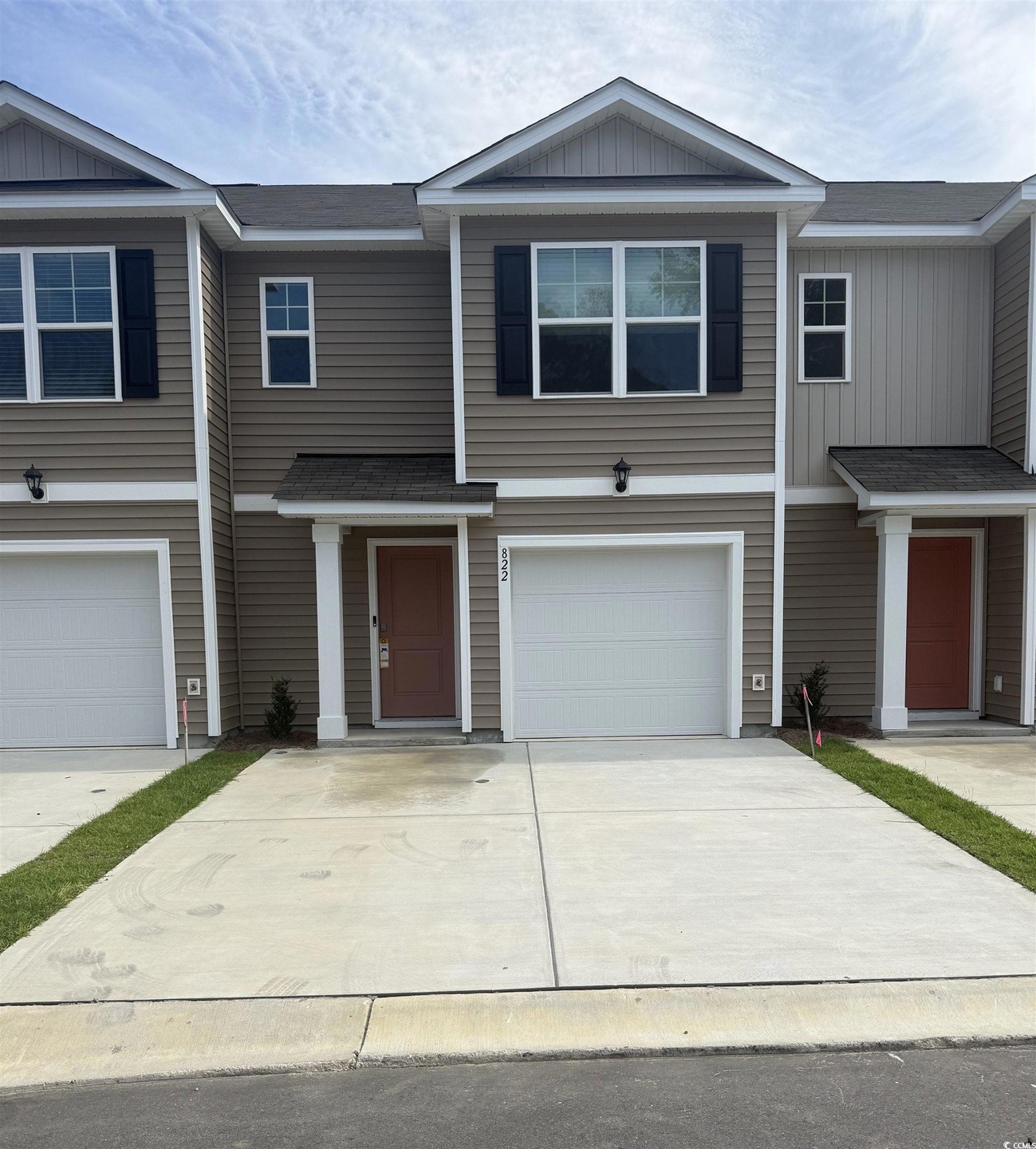 View of front facade with board and batten siding, driveway, an attached garage, and roof with shingles