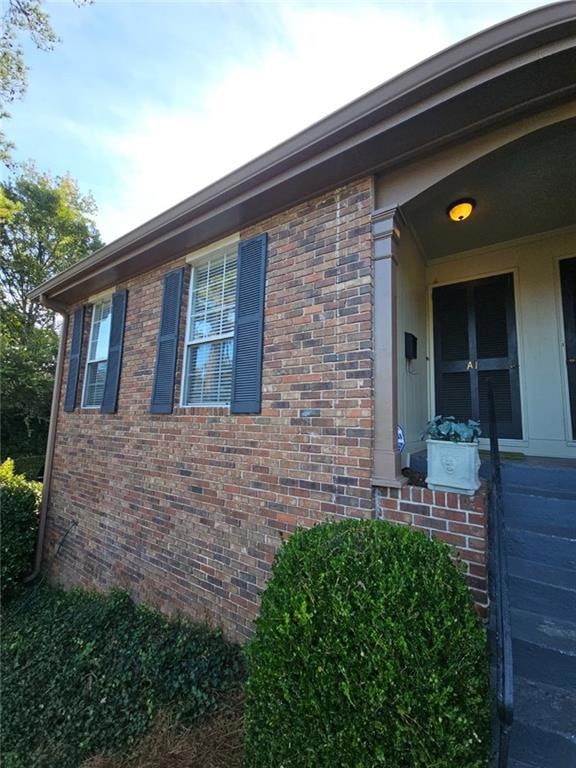 View of side of home featuring brick siding and a porch