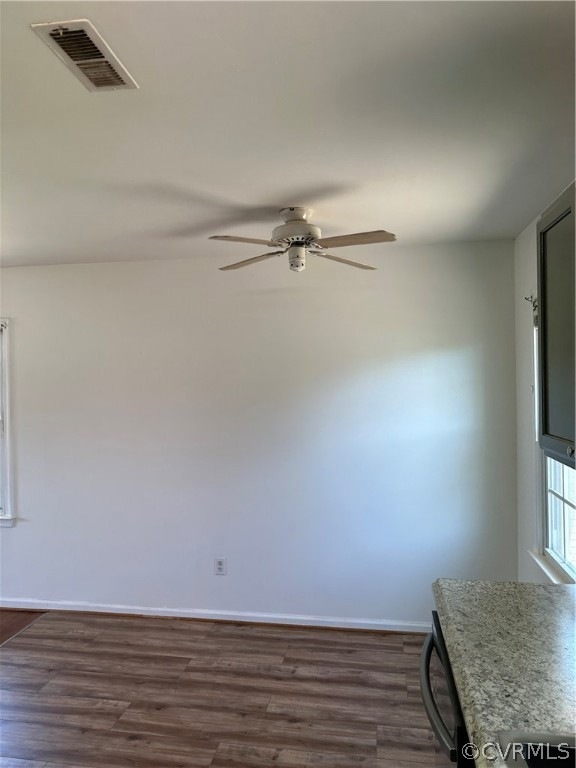 Unfurnished dining area featuring ceiling fan and dark hardwood / wood-style flooring