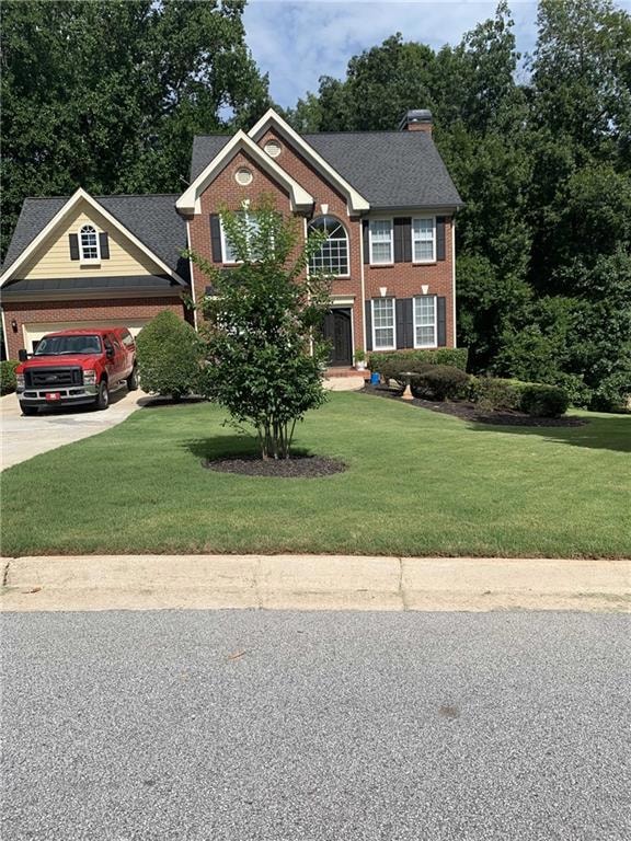 Colonial house with driveway, brick siding, and a 