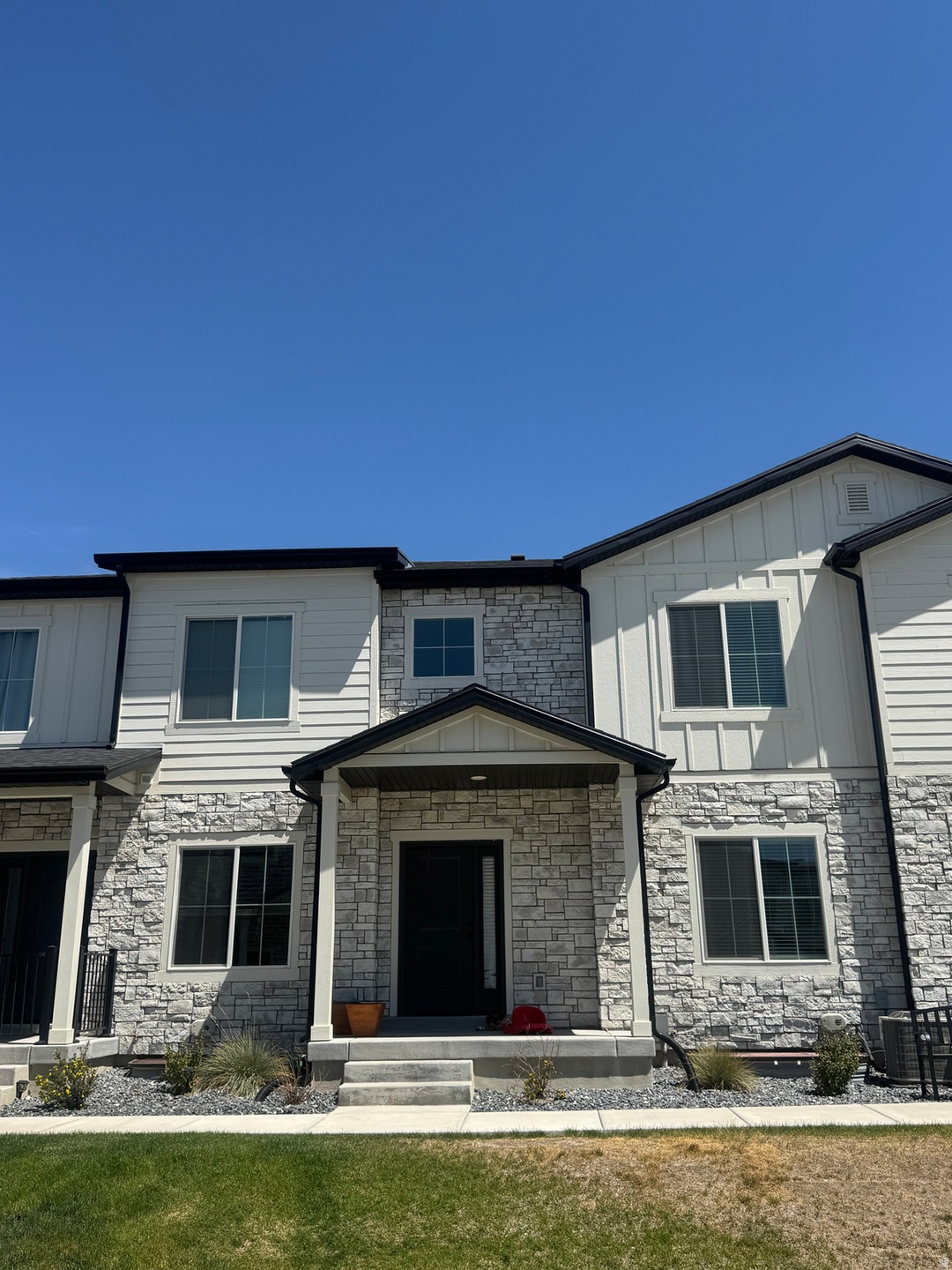 View of front of property with stone siding, covered porch, a front yard, and board and batten siding