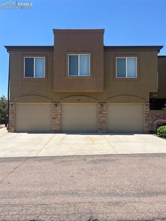 Multi unit property featuring stucco siding, an attached garage, and driveway