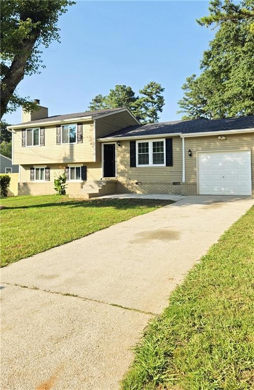 Tri-level home featuring driveway, an attached garage, and a chimney