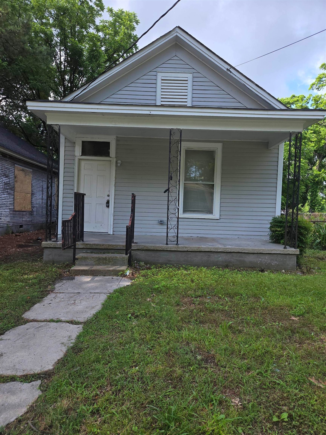 Shotgun-style home with covered porch and a front yard