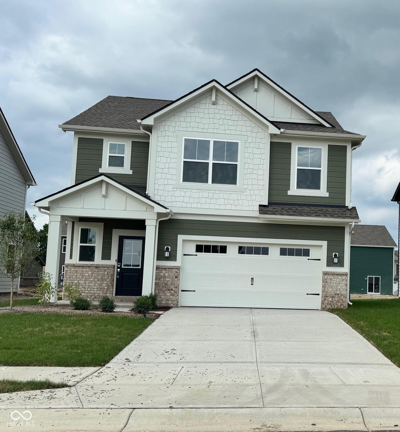 craftsman inspired home with a garage, concrete driveway, a front yard, and brick siding