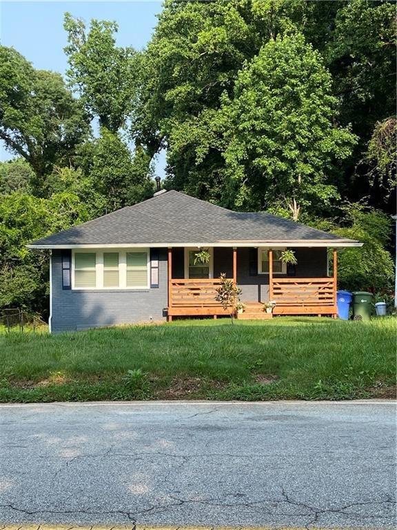Ranch-style home featuring covered porch, brick siding, and roof with shingles