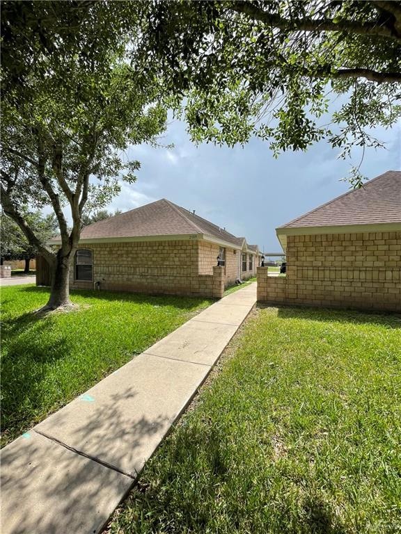 View of side of property featuring a lawn and a shingled roof