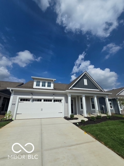 view of front of home with driveway, an attached garage, covered porch, board and batten siding, and a front yard