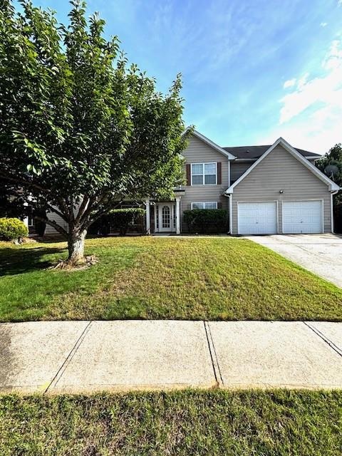 View of front facade featuring a front lawn, an attached garage, and concrete driveway