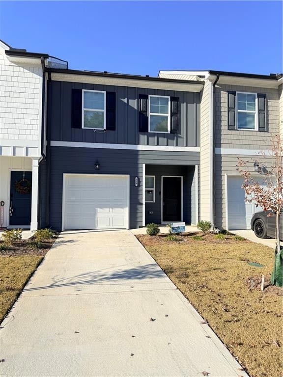 View of front of property with concrete driveway, an attached garage, and board and batten siding