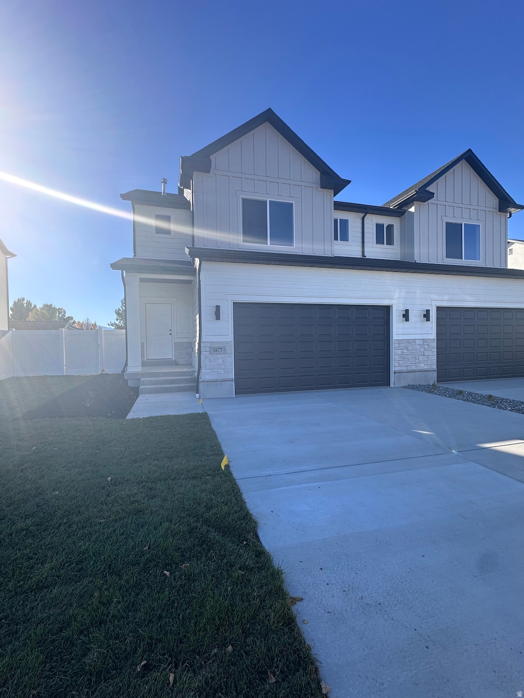 View of front facade with board and batten siding, concrete driveway, an attached garage, and stone siding