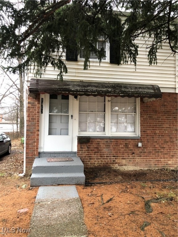 Entrance to property with brick siding and covered porch