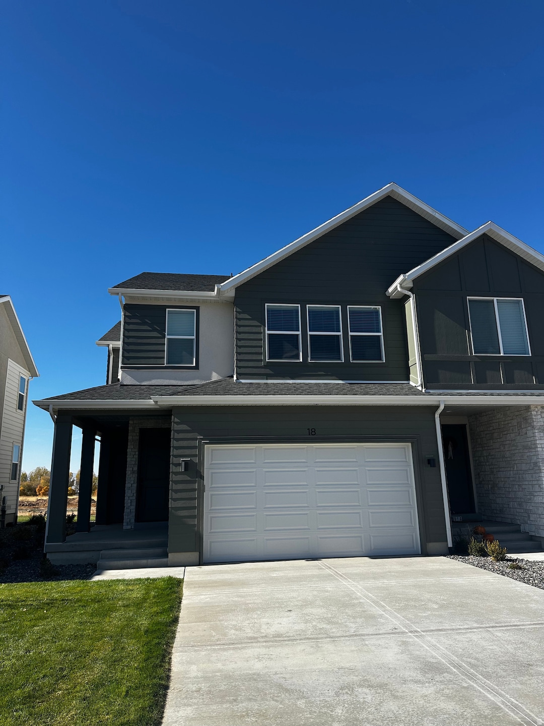 View of front facade featuring driveway, brick siding, a porch, a garage, and a shingled roof