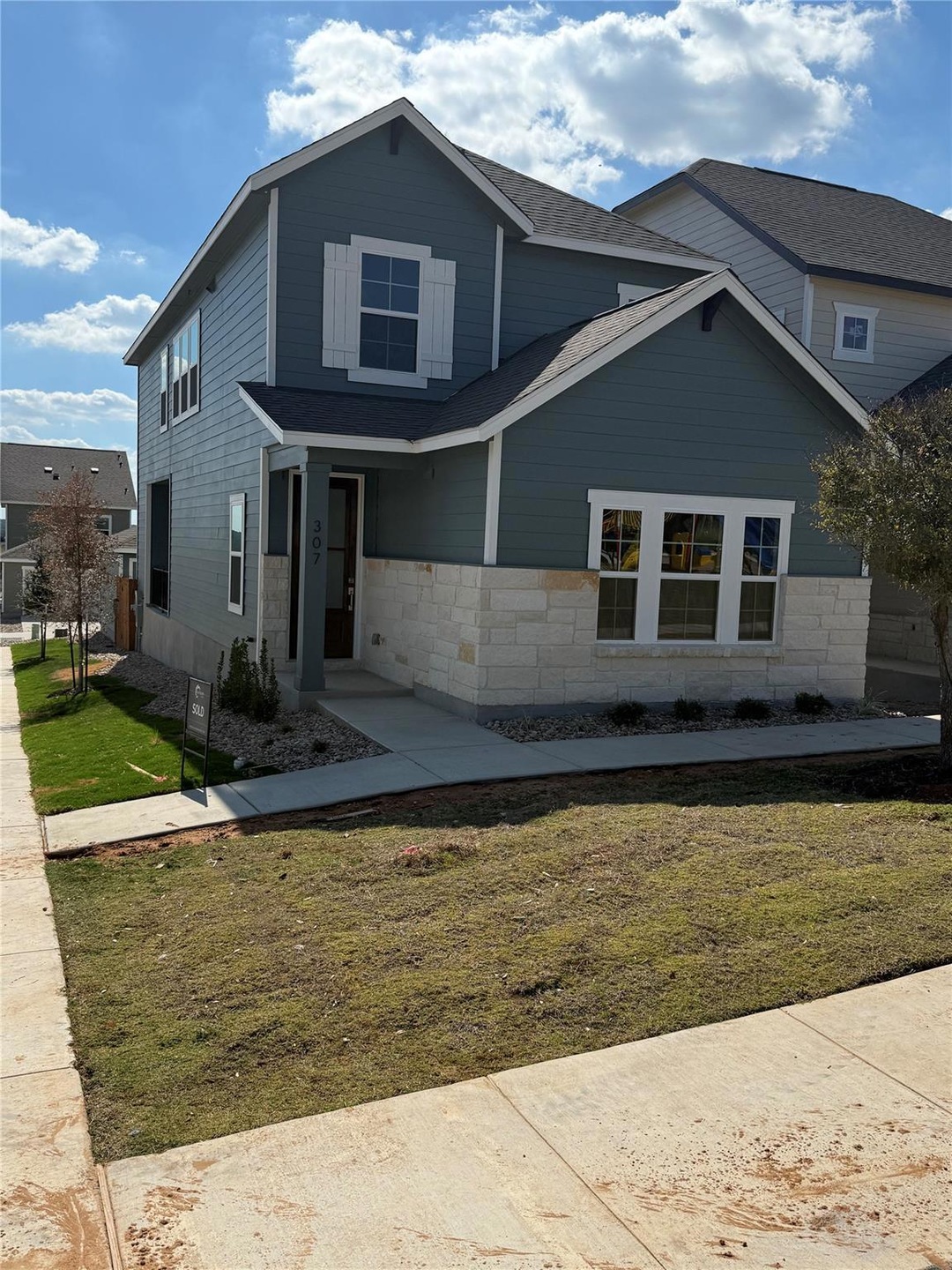View of front of home featuring a front yard, stone siding, and roof with shingles