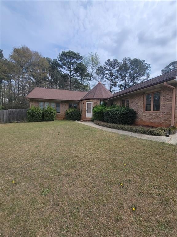 Ranch-style home with brick siding, fence, and a f