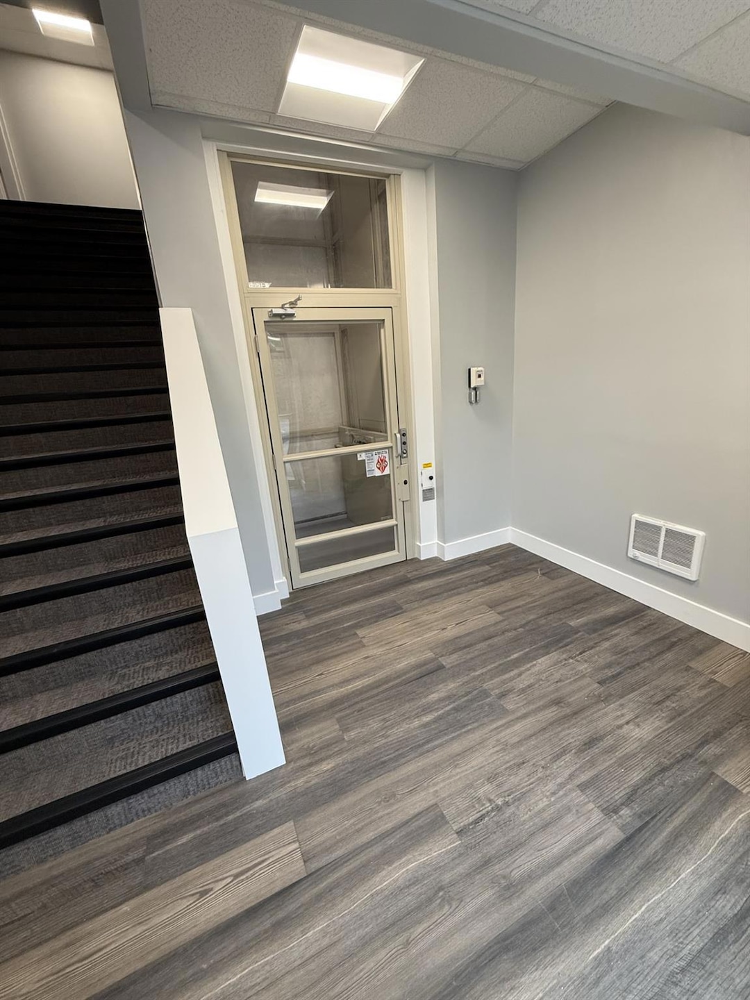 Basement featuring stairway, baseboards, and dark wood finished floors